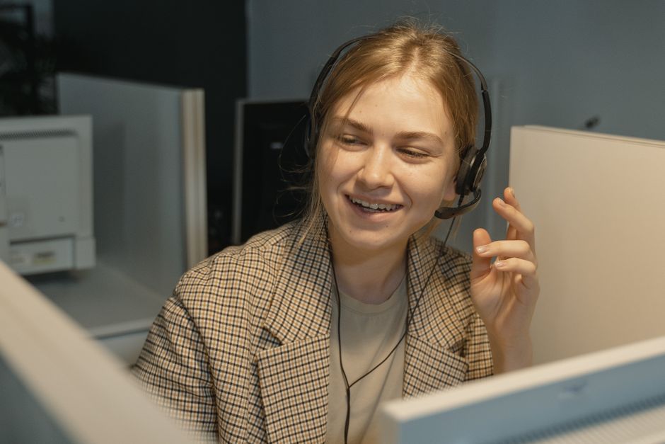 Nasmijana djelatnica s headsetom komunicira s klijentom tijekom razvoja projekta